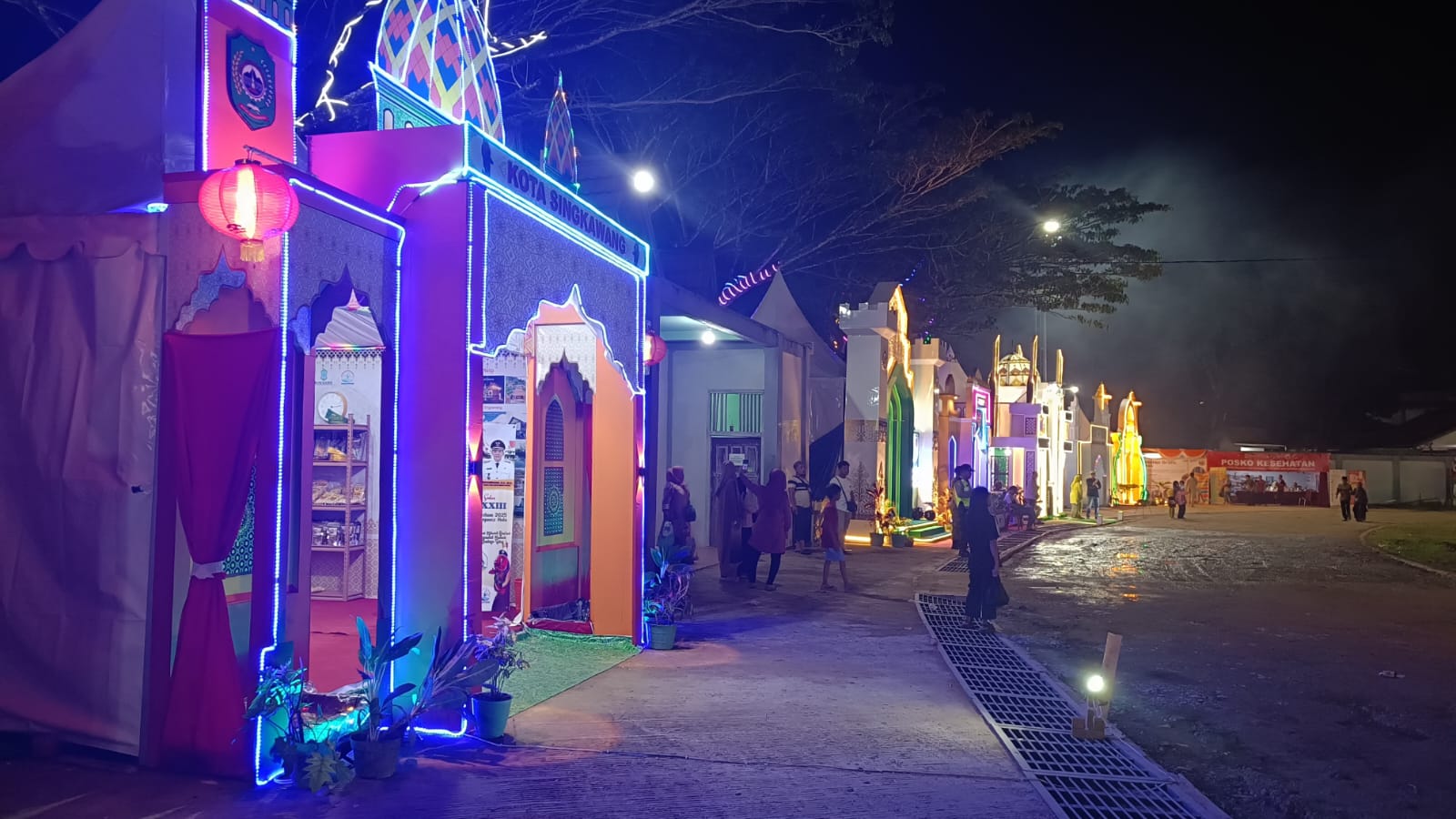 Suasana stand pameran MTQ XXXIII di Kapuas Hulu pada malam hari, gemerlap lampu dan ramainya pengunjung menciptakan atmosfer meriah.