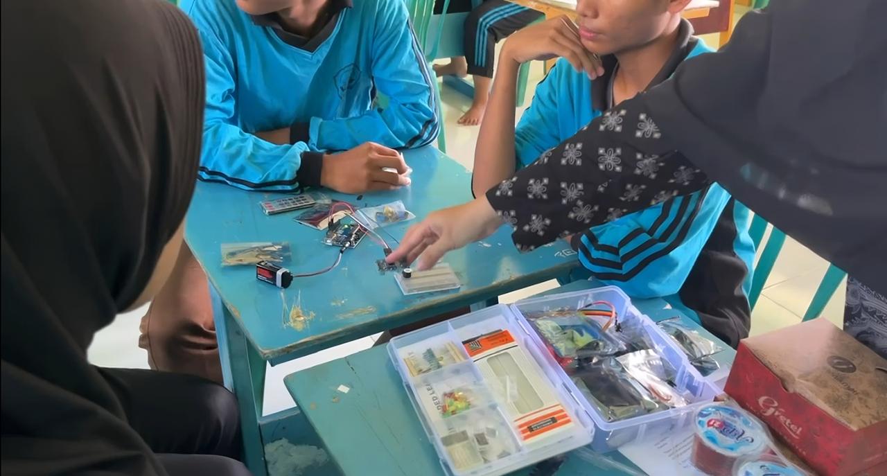 Siswa praktik merakit Arduino dan sensor dalam pelatihan teknologi mitigasi bencana.
