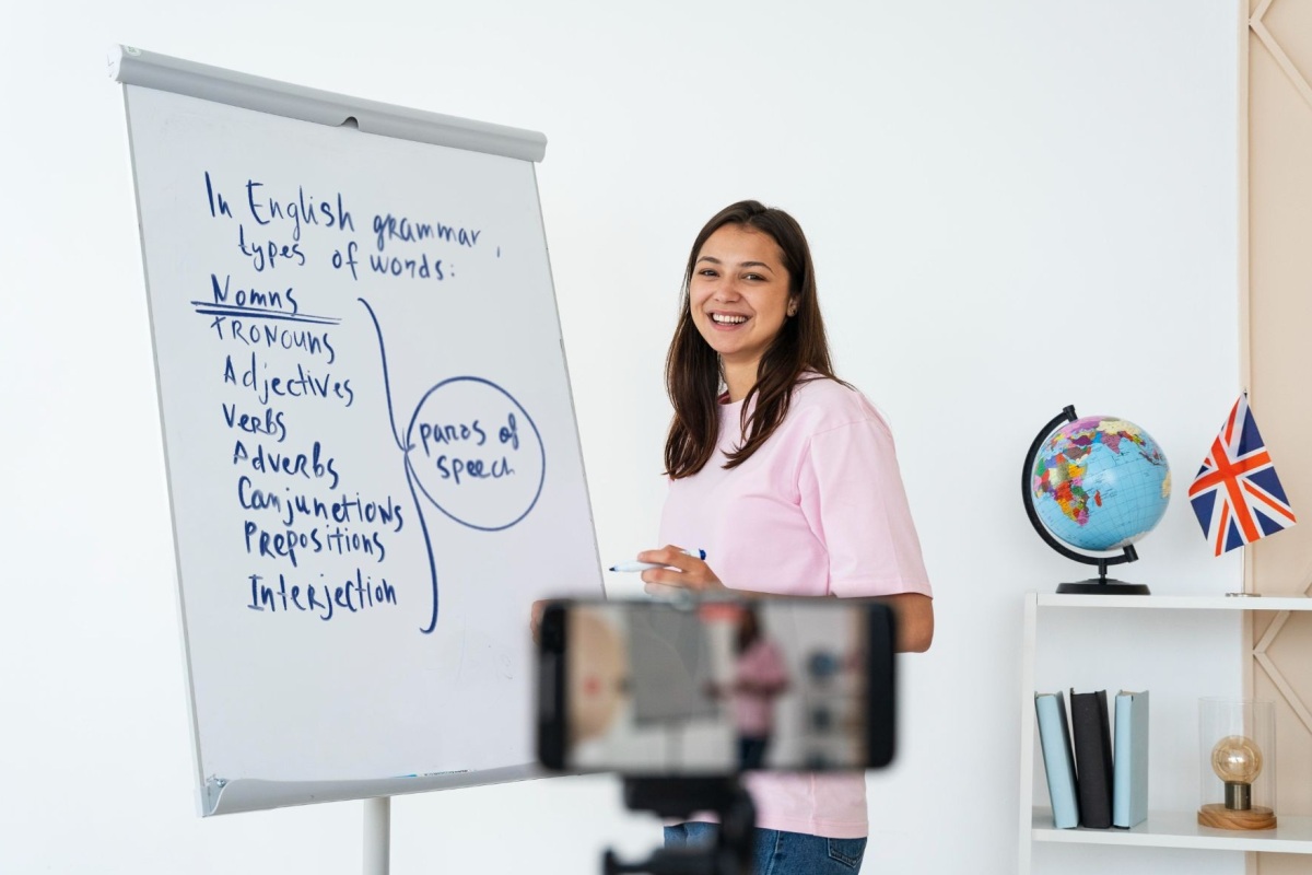 Ilustrasi pengajar bahasa Inggris sedang menjelaskan materi tata bahasa di kelas persiapan TOEFL/IELTS.