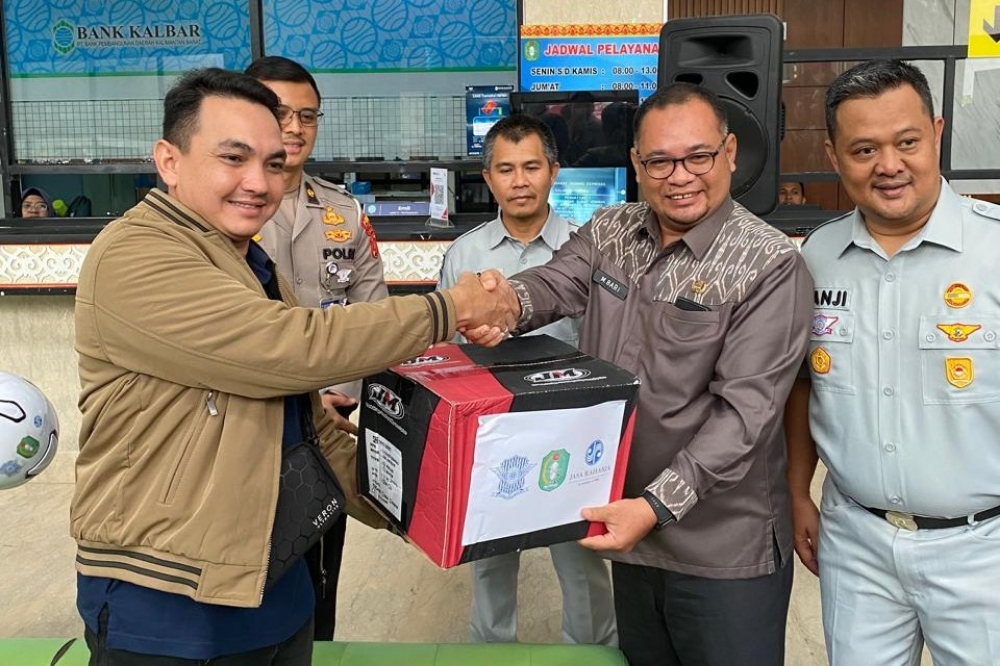 Kepala Bapenda Kalbar, Mohammad Bari menyerahkan helm kepada wajib pajak di hari keselamatan berlalu lintas, Jumat (19/9) pagi.