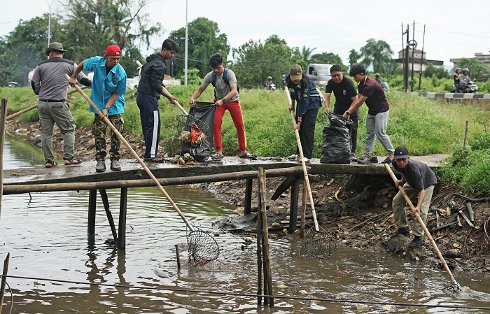 KEPEDULIAN PEMUDA: Sejumlah anak muda dari berbagai organisasi kepemudaan berpartisipasi dalam mempersihkan sampah di Parit Jalan Pararel, Pontianak Timur.