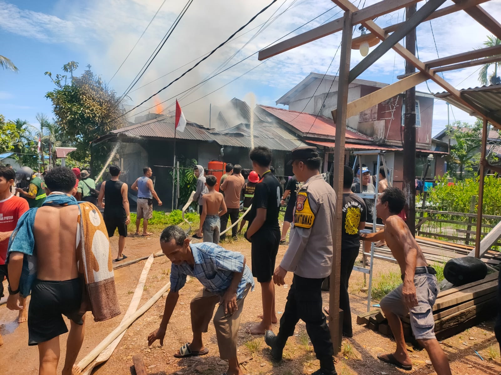 TERBAKAR: Warga bersama petugas pemadam kebakaran dan kepolisian bahu membahu memadamkan api yang melahap rumah di Desa Sungai Ambawang Kuala.