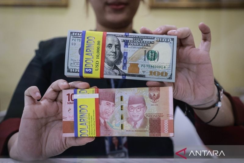 KURS RUPIAH: Petugas menunjukkan uang pecahan rupiah dan dolar AS di gerai penukaran mata uang asing Melawai, Jakarta. Sepanjang pekan ini, rupiah melemah.