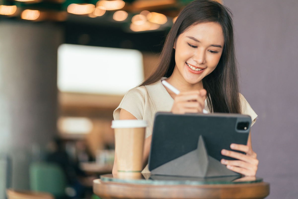 Ilustrasi seorang perempuan sedang menggunakan tablet dengan stylus untuk kegiatan desain dan editing.