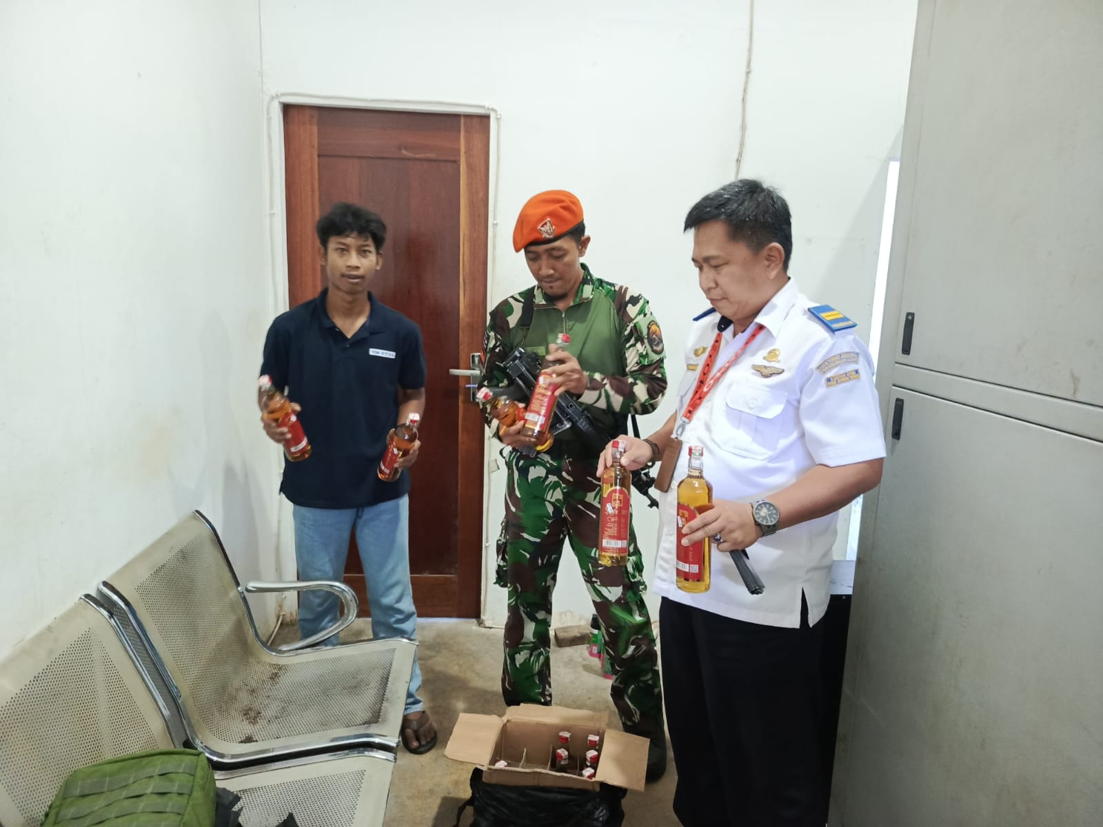 Petugas Satgas Korpasgat dan Avsec Bandara Douw Aturure Nabire memeriksa barang bukti 12 botol minuman keras ilegal yang berhasil diamankan sebelum dikirim ke Sugapa, Senin (13/10).
