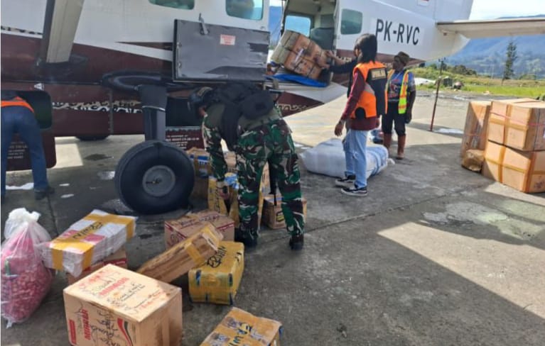 Personel Satgas Korpasgat bersama petugas bandara membantu proses bongkar muat logistik di Bandara Ilaga, Kabupaten Puncak.