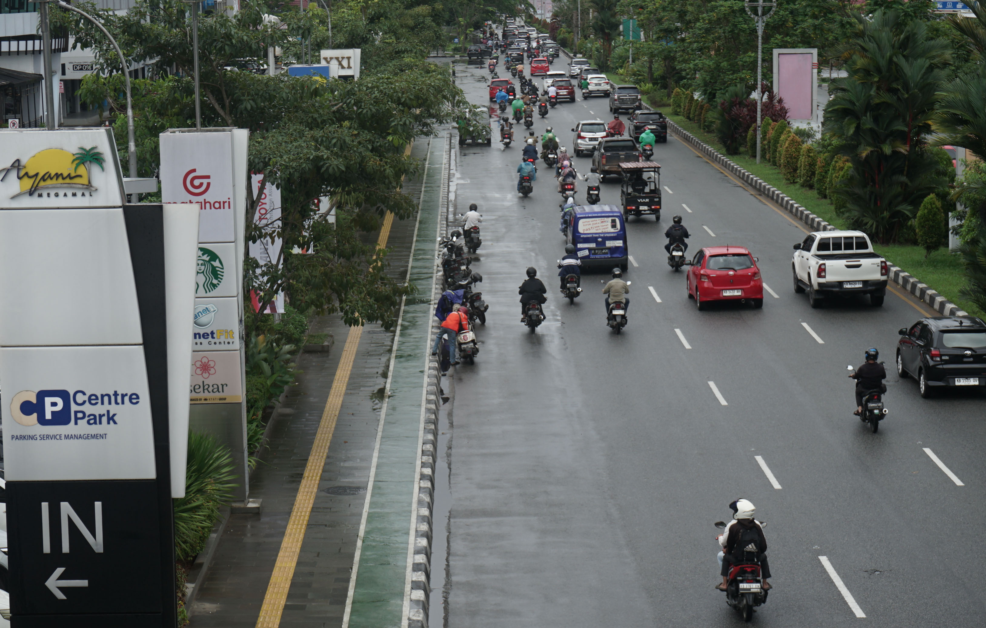 CUACA HUJAN:Sejumlah pengendara menepi untuk memasang mantel hujan saat hujan turun di Jalan Ahmad Yani.  Hujan yang disertai angin kencang yang melanda Kota Pontianak harus diwaspadai oleh warga.