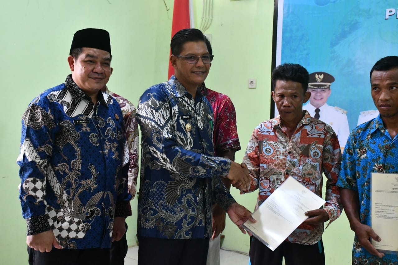 SERAHKAN: Wakil Bupati Kayong Utara Amru Chanwari menyerahkan secara simbolis 472 sertipikat tanah kepada warga Transmigrasi Tanjung Satai, Kecamatan Pulau Maya.