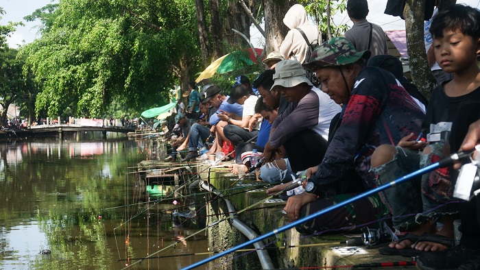 LOMBA MANCING: Sejumlah peserta beradu keberuntungan mengikuti lomba mancing ikan lele yang ditabur panitia di Parit Sungai Jawi, Minggu (19/10).