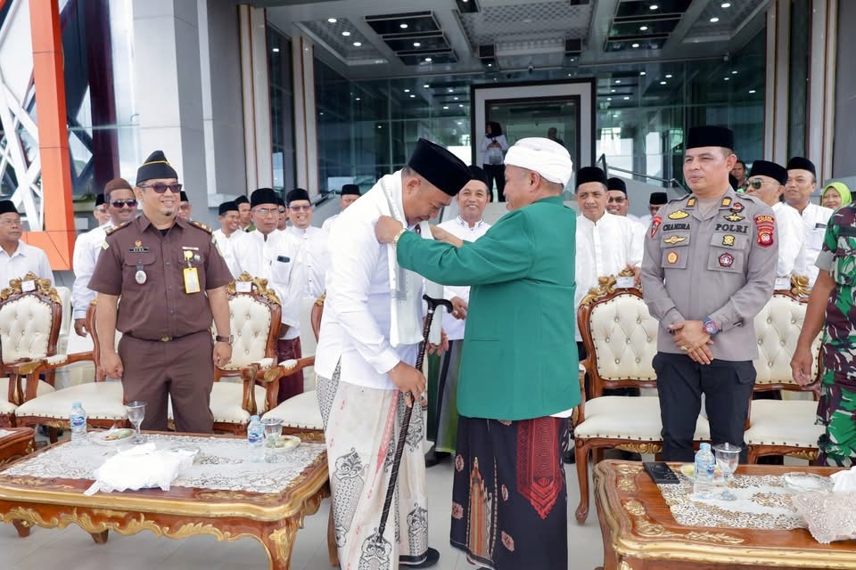 TERIMA SORBAN : Bupati Ketapang, Alexander Wilyo, menerima sorban dan tongkat dari Rois Syuriah PCNU Ketapang, KH. Jemaie Makmur, pada peringatan HSN 2025, Rabu (22/10).