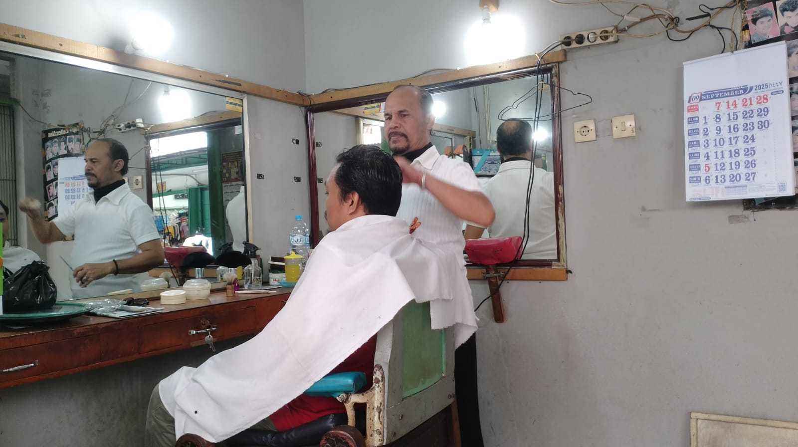 PANGKAS RAMBUT: Bang Uddin saat memangkas rambut pelanggan di kiosnya di Pasar Tengah, Pontianak.