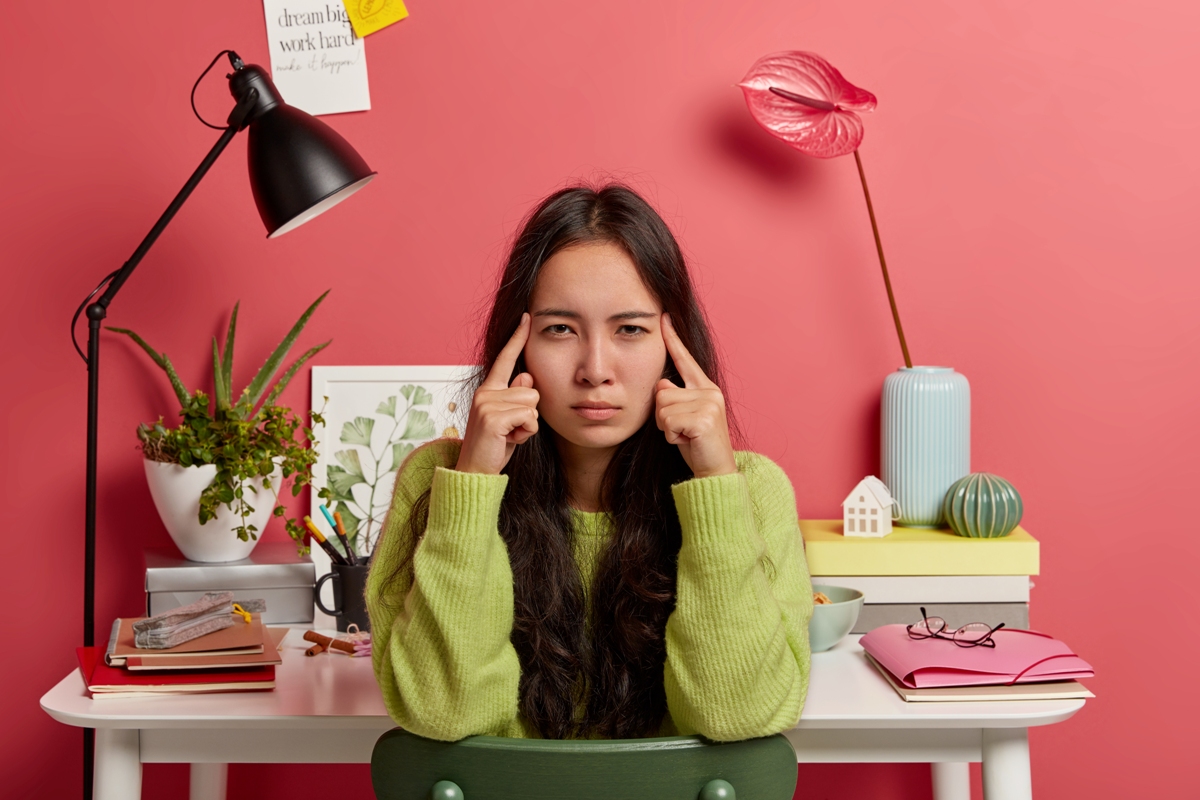 Ilustrasi seorang perempuan mengalami stres dan kesulitan berkonsentrasi saat belajar atau bekerja akibat tekanan mental.