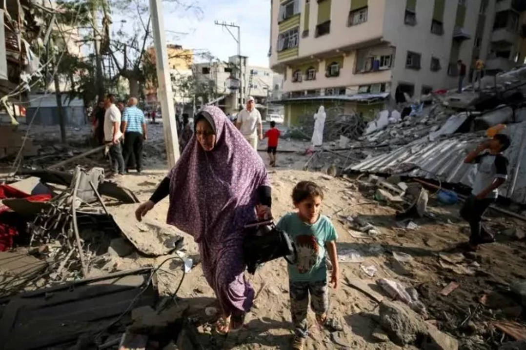 Warga Palestina berjalan diantara puing bangunan yang hancur akibat serangan di Jalur Gaza. Situasi kemanusiaan di wilayah tersebut terus memburuk.