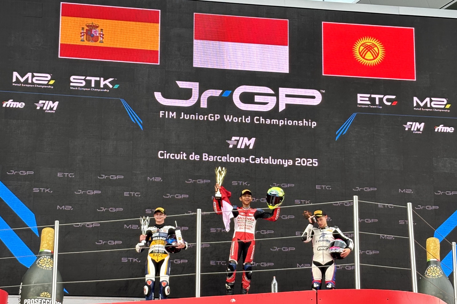 M. Kiandra Ramadhipa di podium utama European Talent Cup Barcelona 2025, mengibarkan bendera Merah Putih untuk Indonesia.