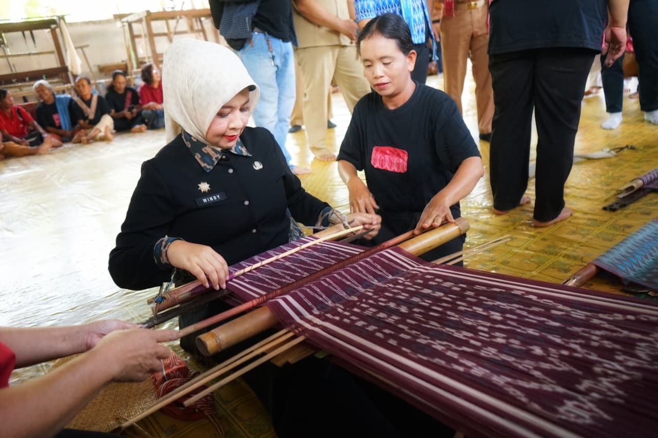 TENUN : Kepala Disporapar Kalbar Windy Prihastari mencoba alat tenun saat membuka Workshop Tenun di Desa Kumpang Ilong, Kabupaten Sekadau.