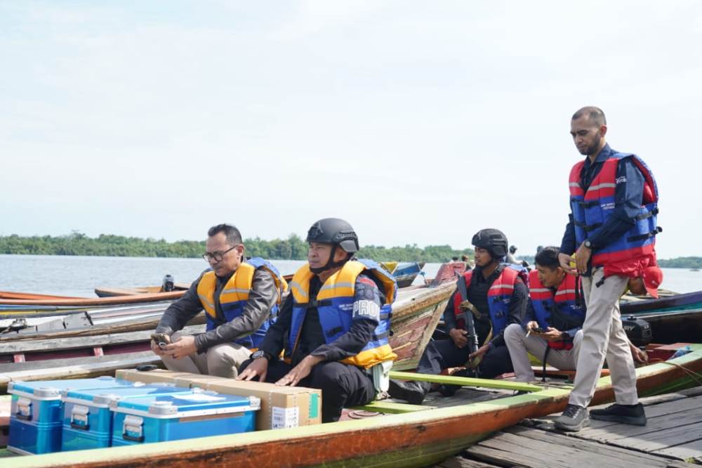 Petugas membawa uang rupiah dalam kegiatan layanan kas keliling susur sungai oleh Bank Indonesia.