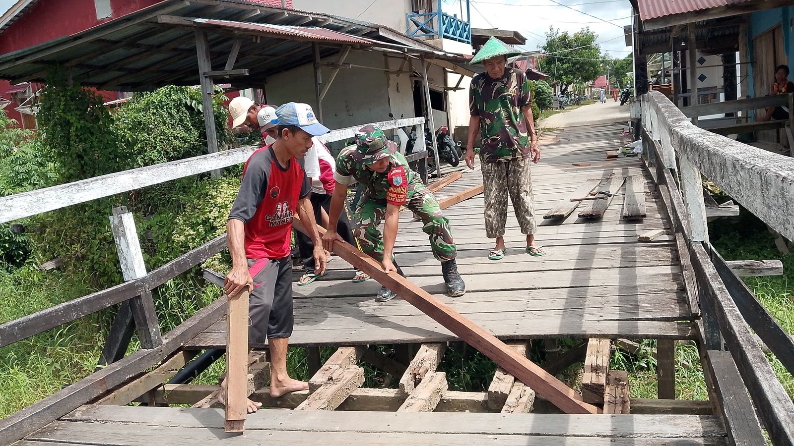 Babinsa dan warga Mekar Jaya bergotong royong memperbaiki jembatan yang rusak di Silat Hilir.