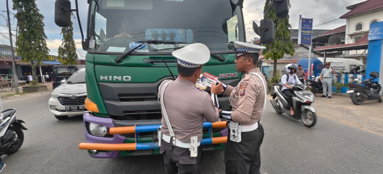 (Kiri) Petugas Satlantas Polres Kubu Raya menempel stiker sosialisasi kepada kendaraan berat di Simpang Kapur. (Kanan) Petugas menegur pengendara motor yang tidak memakai helm dan kelengkapan kendar