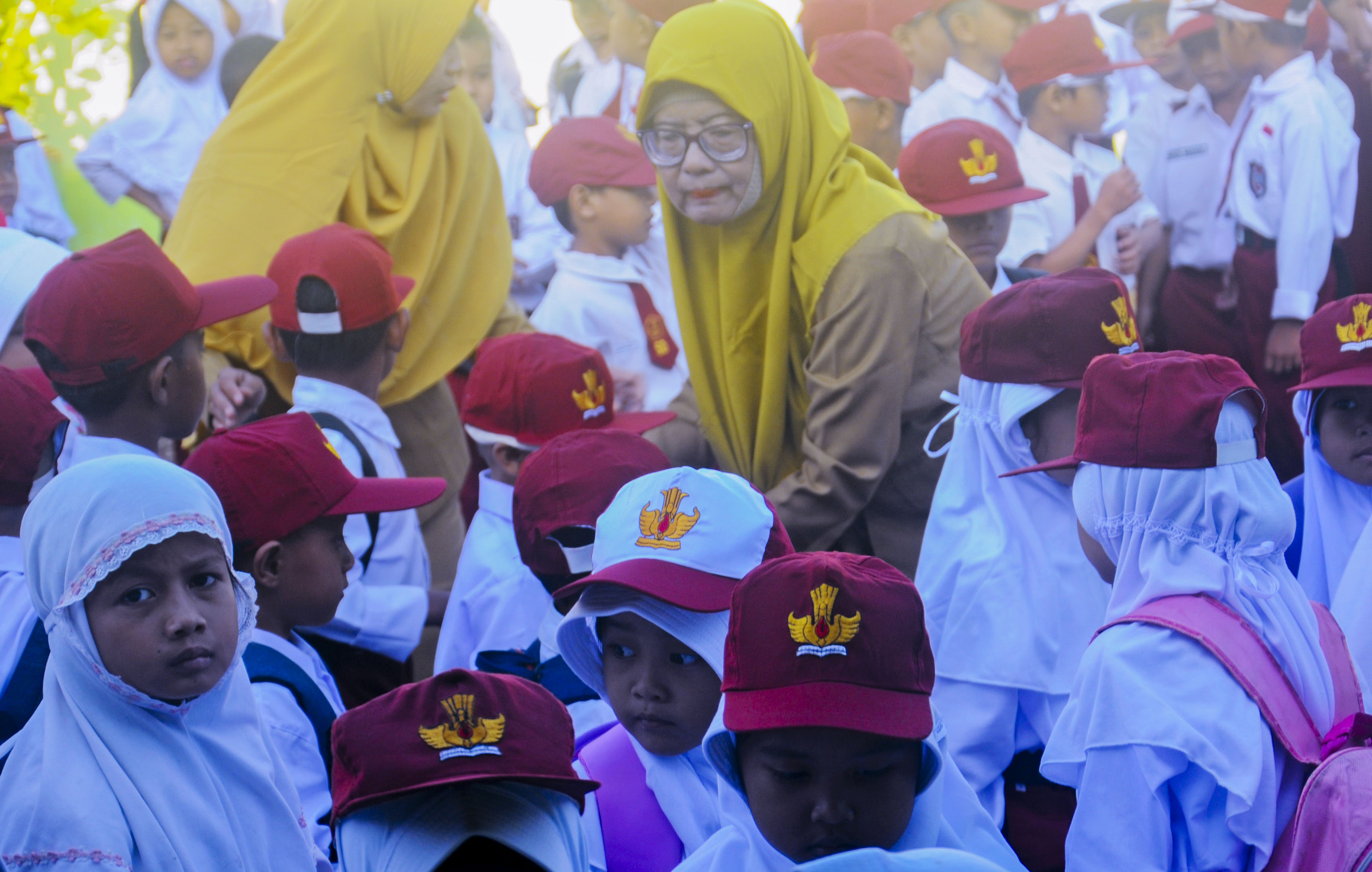 BARISAN: Seorang guru sekolah dasar merapikan barisan muridnya saat upacara bendera.