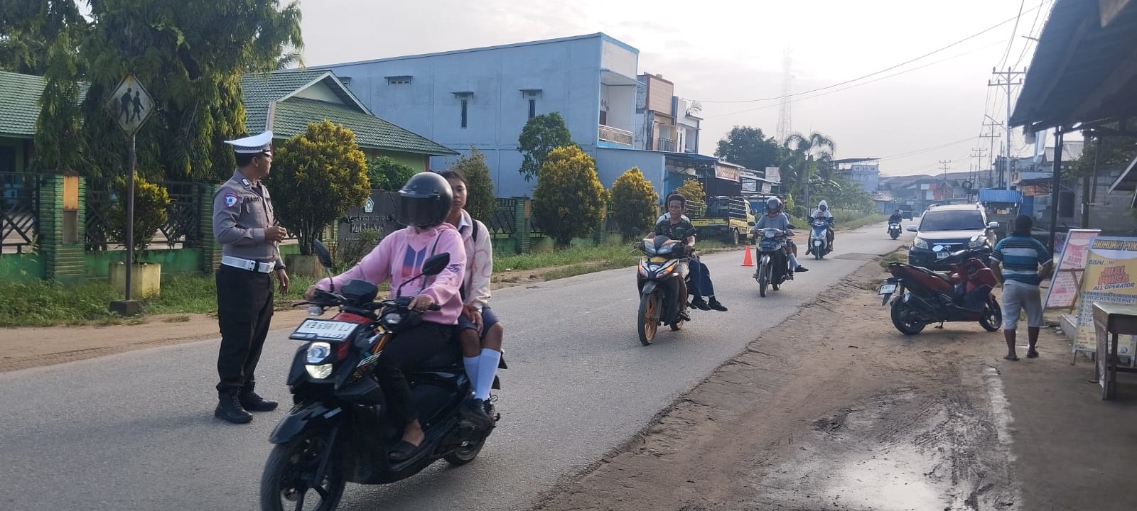 PENGATURAN : Anggota Polsek Mempawah Hulu saat melakukan pengaturan lalu lintas di lingkungan sekolah dan Pasar Karangan.