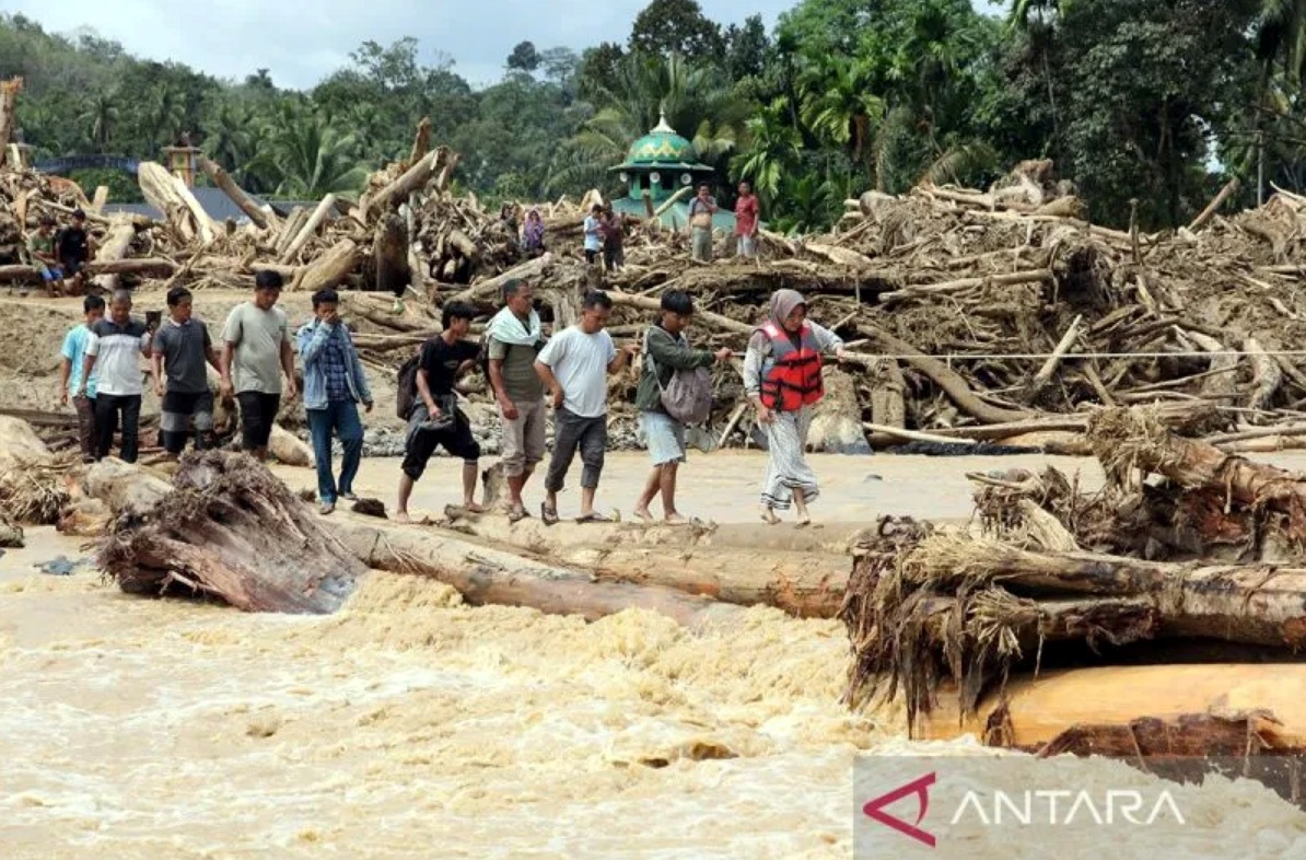 Warga berjalan melintasi sungai dengan jembatan darurat di Desa Aek Garoga, Kecamatan Batang Toru, Kabupaten Tapanuli Selatan, Sumatera Utara, Sabtu (29/11).