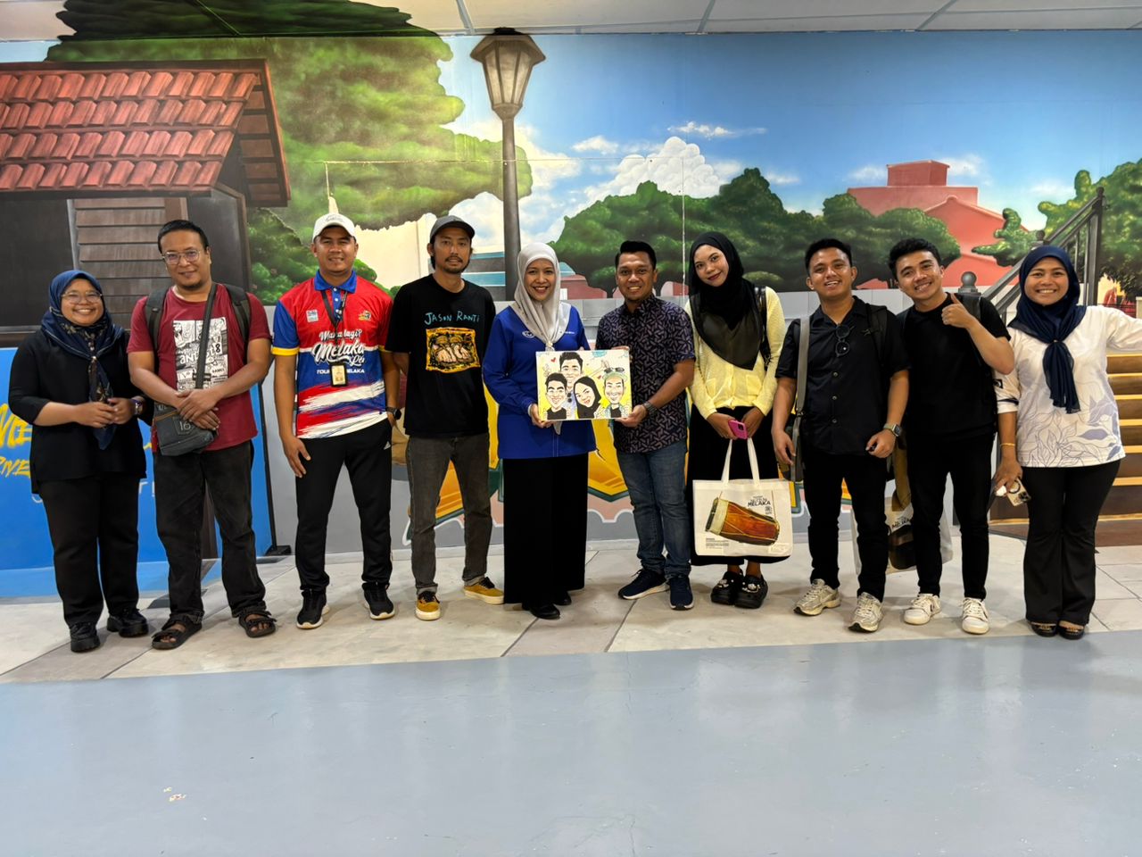 KENANGAN : Secretary General WYF, Dato&rsquo; Norsabrina Mohd Noor (tengah), memberikan kenang-kenangan berupa lukisan karikatur kepada peserta famtrip saat berkunjung ke Galeri 3D &lsquo;Keajaiban Dunia&rsquo; di Mela