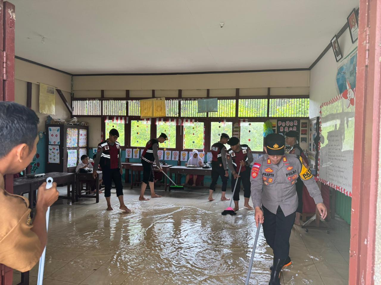 Sejumlah personil Samapta Polres Sambas saat membantu SD N 15 Kartiasa bersih bersih karena banjir, sehingga ulangan semester bisa dilaksanakan.