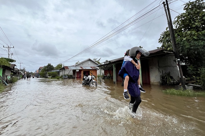 AIR PASANG : Seorang Ibu sedang menggendong anaknya melintas di genangan air di Jalan Pramuka, Sungai Rengas ,Kabupaten Kubu Raya. Air pasang membuat sejumlah jalan tergenang air.