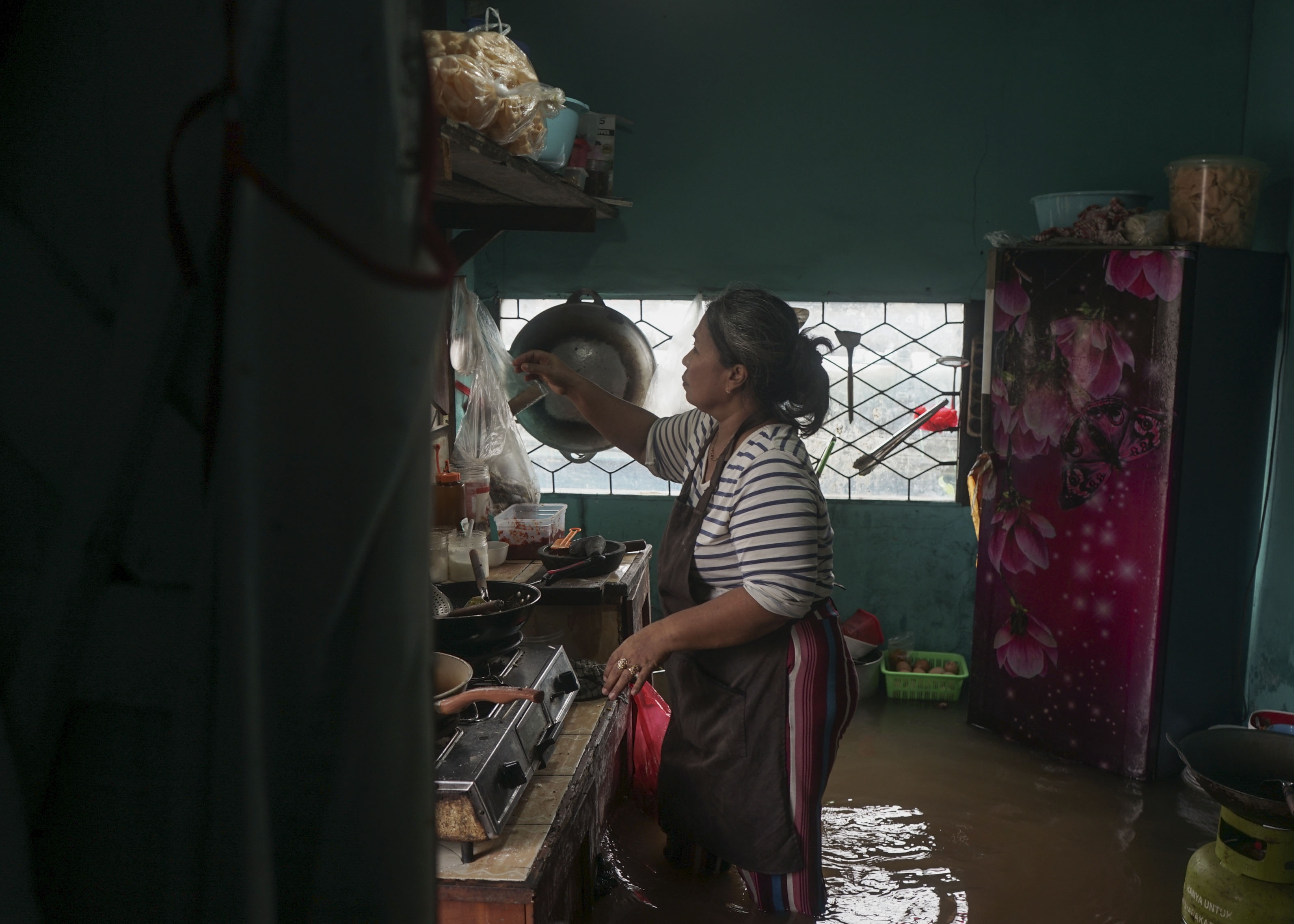TERDAMPAK ROB: Warga di gang Dungun Jalan Gajah Mada beraktivitas di dapur untuk memasak makanan saat pasang air laut menggenangi dapurnya. Sejumlah kawasan di Kota Pontianak terdampak pasang air laut