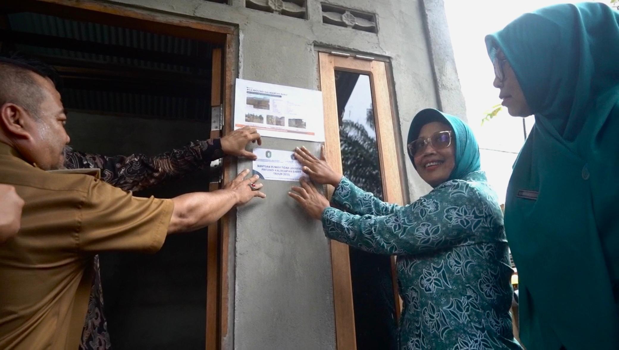 TEMPEL STIKER: Ketua TP PKK Kalimantan Barat Erlina saat menempelkan stiker di rumah warga yang menerima bantuan Rumah Tidak Layak Huni.