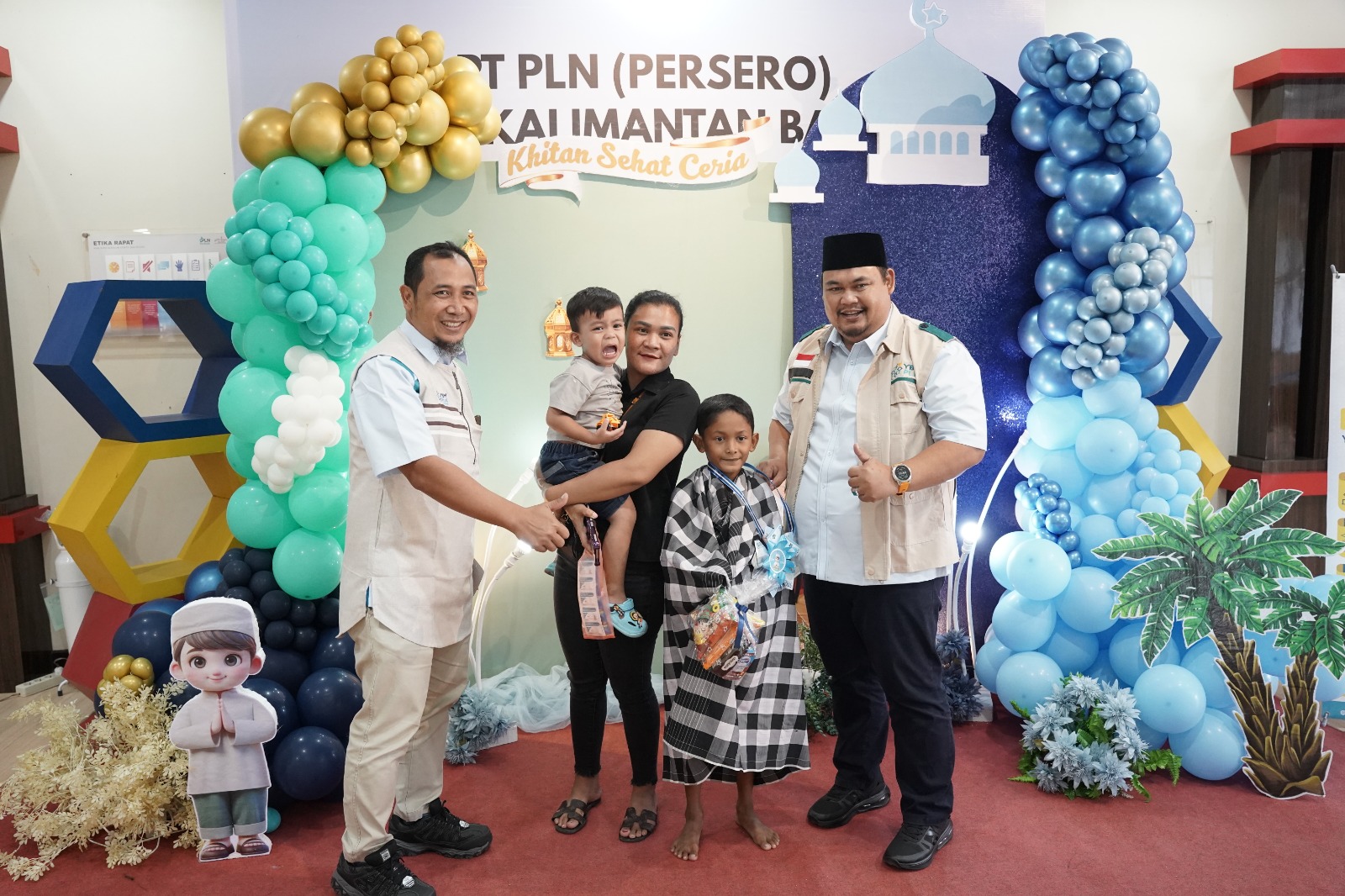 Ketua YBM PLN UID Kalimantan Barat, Mukhlis Zarkasih (kanan), dan Manager Pelaksana Pengadaan PLN UID Kalbar, Syaiful Imron, berfoto bersama salah satu anak yang telah dikhitan. Tampak senyum bahagia