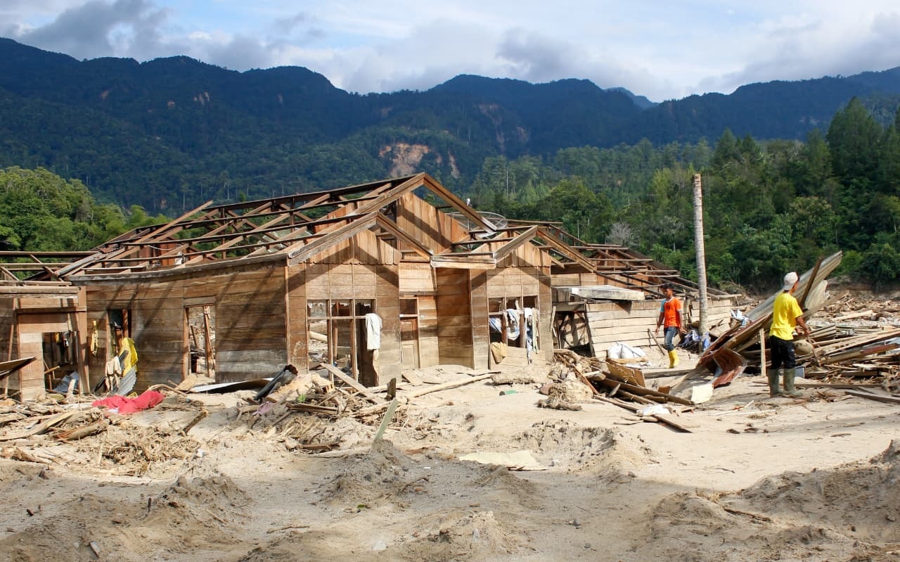 TAK BERSISA: Warga berjalan di tengah puing-puing rumah mereka yang telah rusak akibat diterjang banjir bandang di Desa Kute Reje, Kecamatan Linge, Kabupaten Aceh Tengah.