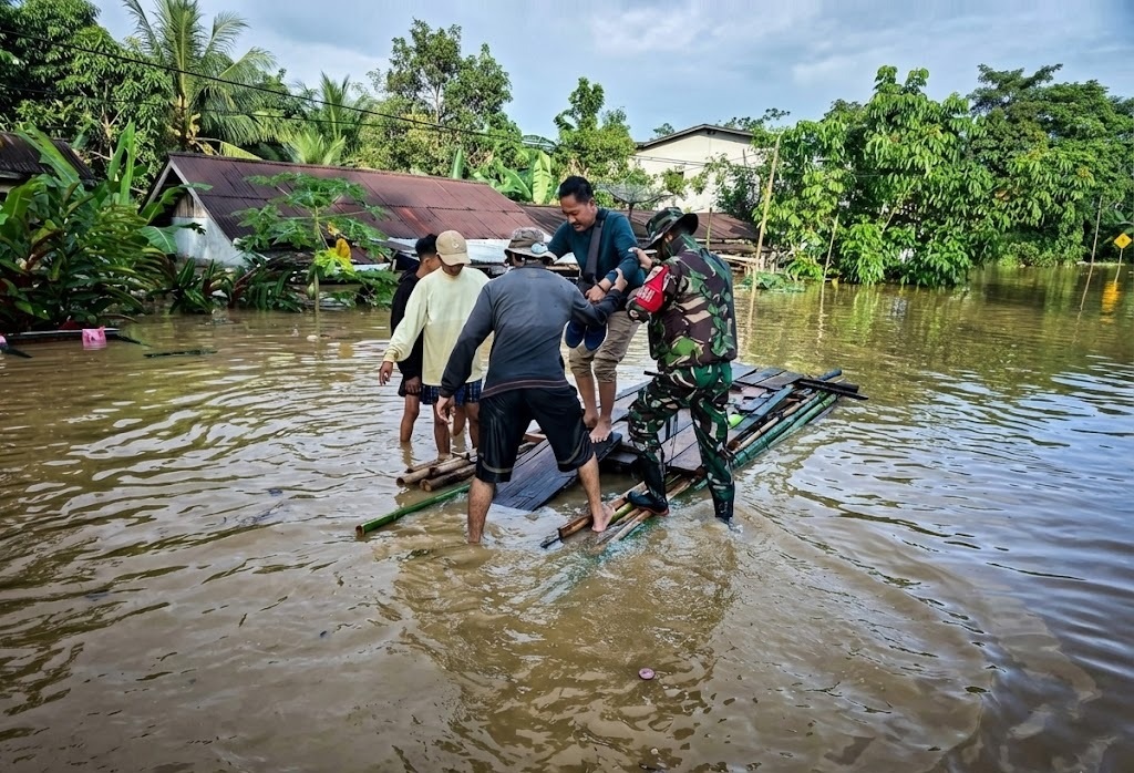BANTU WARGA: Anggota TNI saat membantu warga menyebrangi jalan yang terendam banjir di Jalan Lintas Malindo, Kecamatan Entikong, Kabupaten Sanggau.