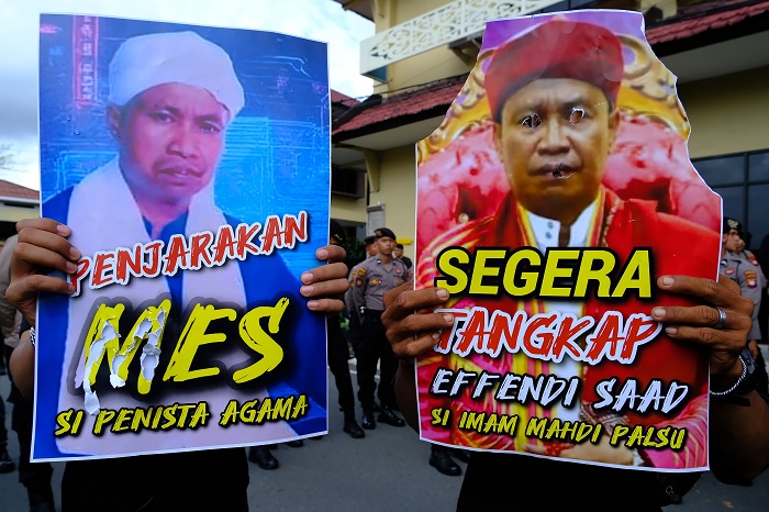 Peserta aksi dari Aliansi Umat Islam Bersatu Kalimantan Barat membawa poster saat berunjuk rasa di Polda Kalimantan Barat, Jumat (9/1/2026). Aliansi Umat Islam Bersatu Kalimantan Barat mendesak Polda Kalbar untuk membubarkan Tarekat Al-Mu?min serta menang