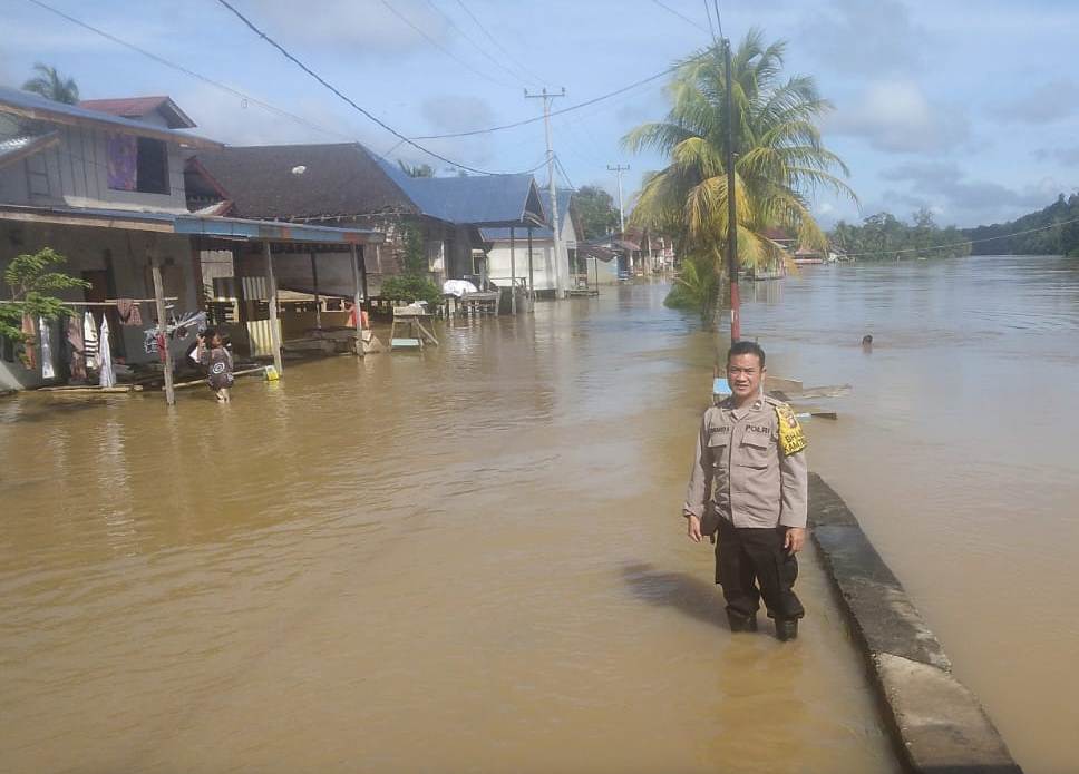 TERENDAM: Personel Polsek Ngabang memantau kondisi banjir di Desa Raja Kecamatan Ngabang pada Senin (12/1).