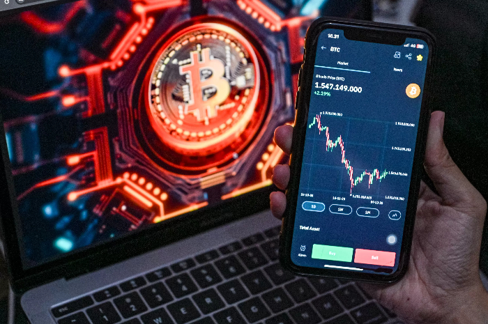 Investor melihat pergerakan kripto Bitcoin melalui handphone.