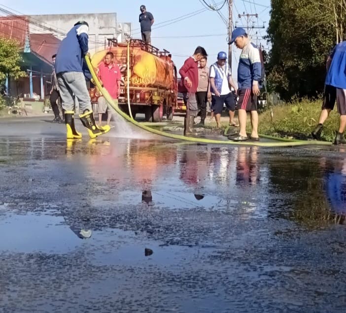 Petugas Damkar Sambas saat cuci jalan yang terkena tumpahan CPO.