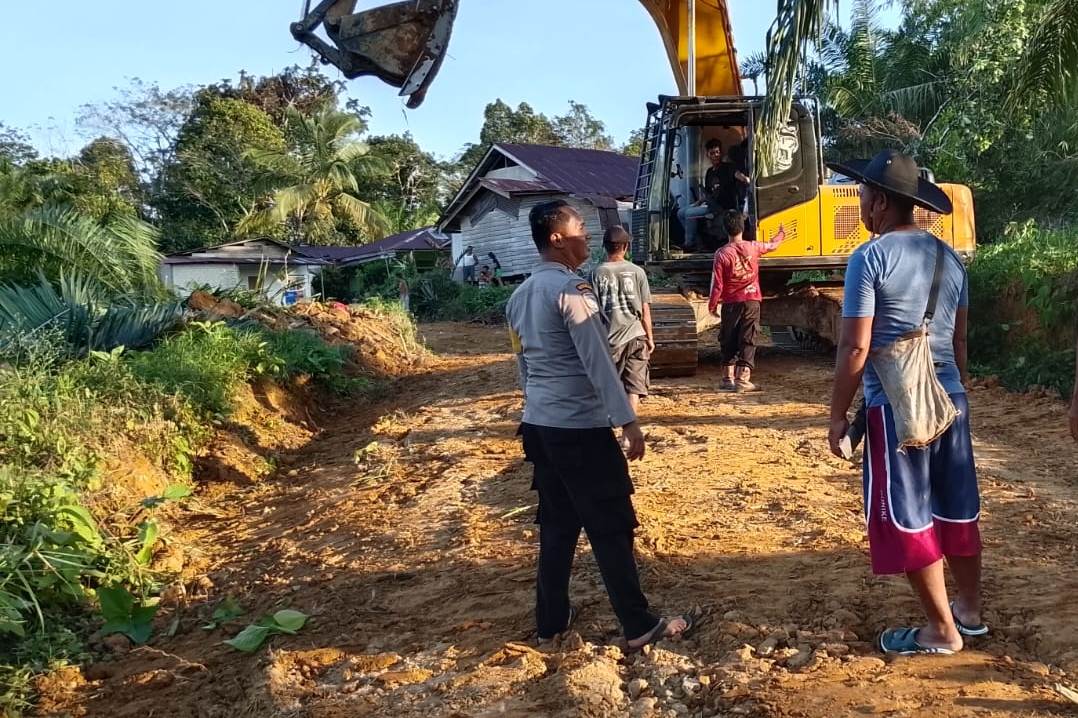 PANTAU: Personel Polsubsektor Jelimpo Kabupaten Landak bersama warga memantau perbaikan jalan di Desa Nyiin pada Jumat (30/1).