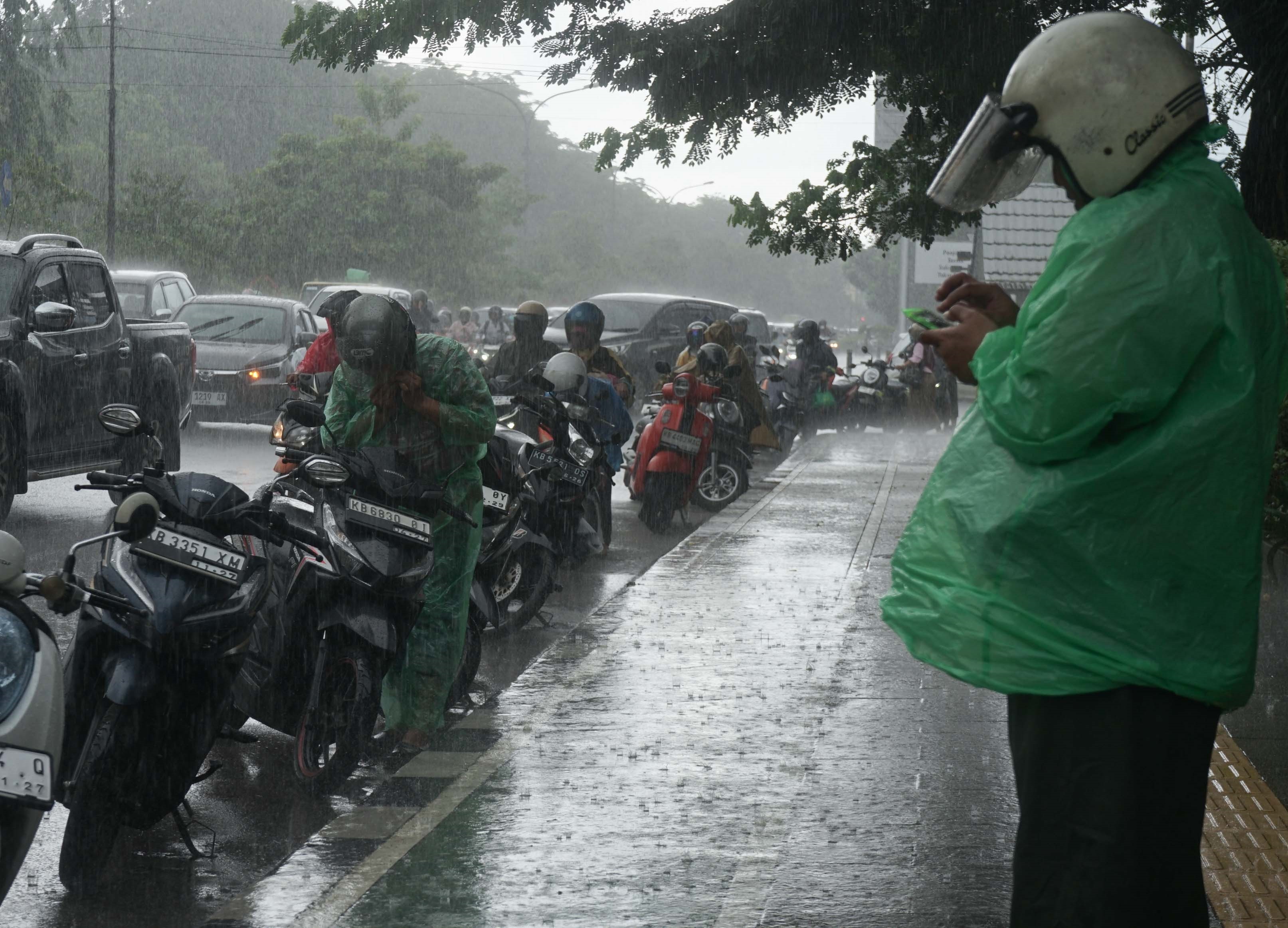 TURUN HUJAN: Sejumlah pengendara berhenti di pinggir Jalan Ahmad Yani, Pontianak, untuk memasang jas hujan. Minggu (1/2) sore, sejumlah wilayah di Kota Pontianak dan sekitarnya mulai turun hujan meski