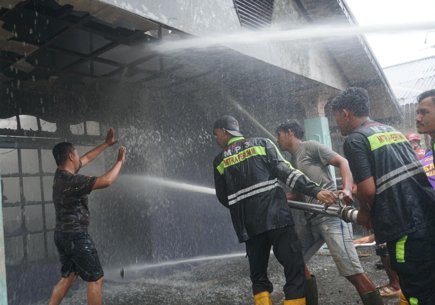 Relawan pemadam kebakaran menyemprotkan air untuk memadamkan rumah yang terbakar di Gang Taslim, Jalan Tanjung Raya 1, Pontianak, Minggu (8/3/2026).