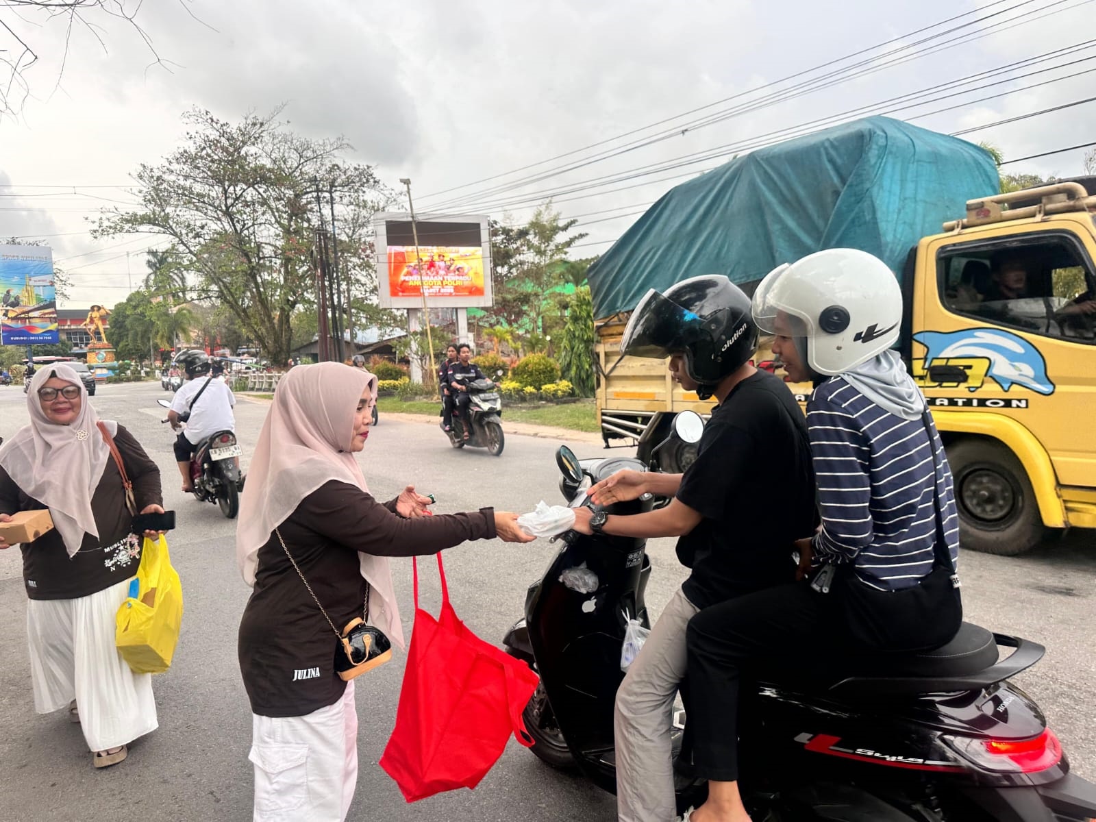 BAGI TAKJIL: Ketua PC Muslimat NU Julina membagikan takjil kepada pengendara.