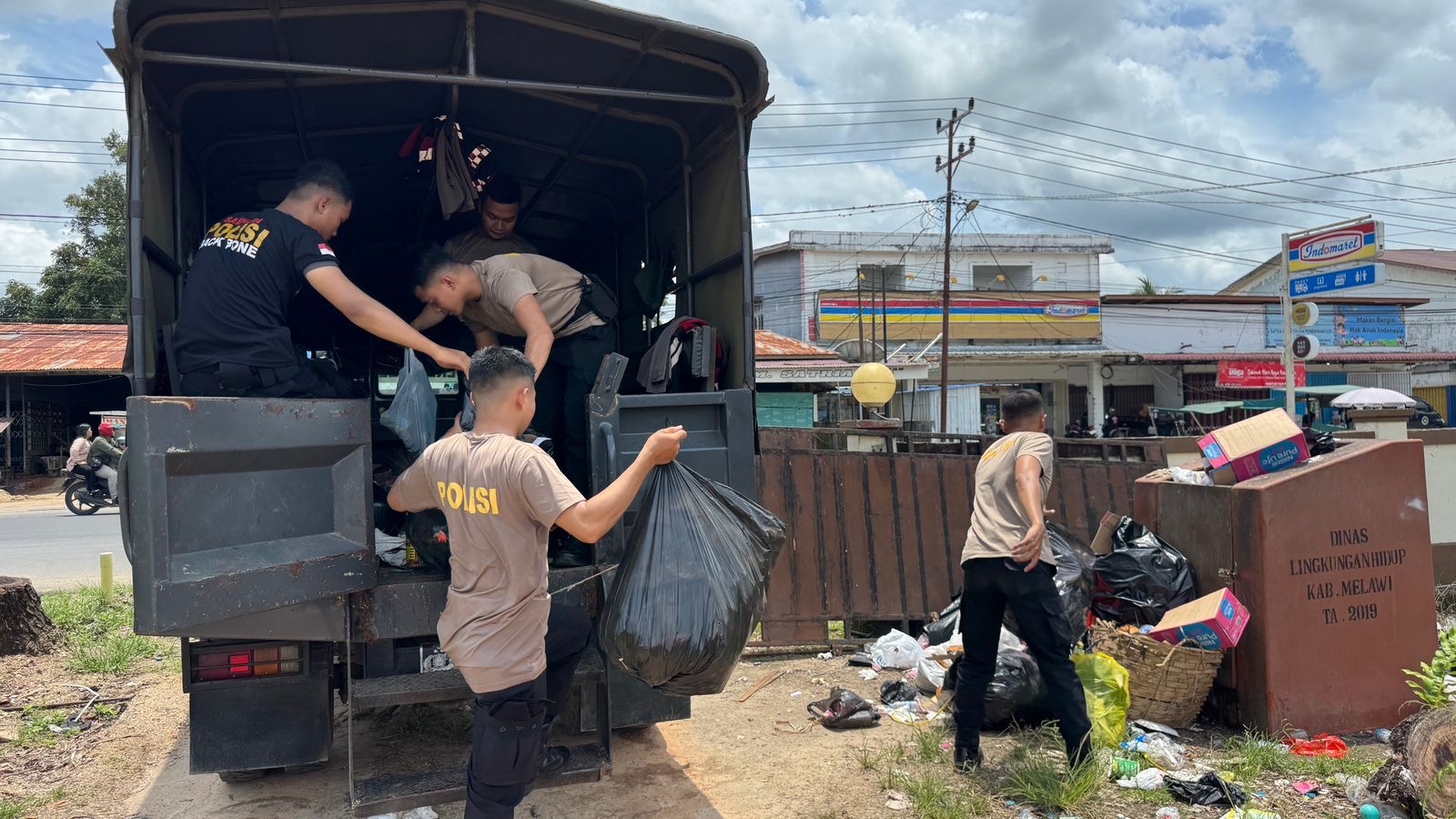 Personel Polres Melawi mengangkut sampah di sekitar Jembatan Melawi II sebagai upaya menjaga kebersihan lingkungan.