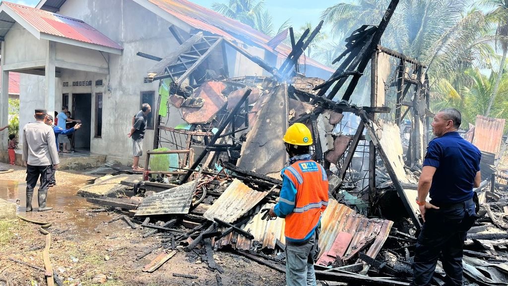 PADAM: Petugas dan warga berjibaku memadamkan api yang membakar rumah kontrakan.