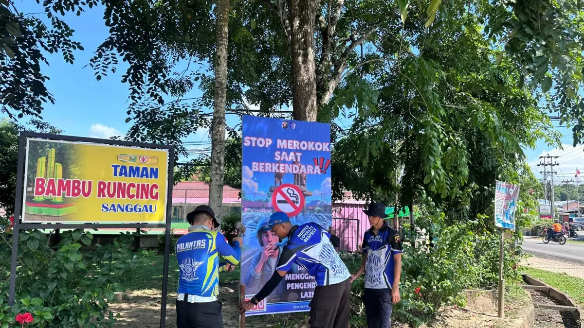 Petugas memasang banner imbauan larangan merokok dan keselamatan berkendara di Jalan Raya Sanggau.