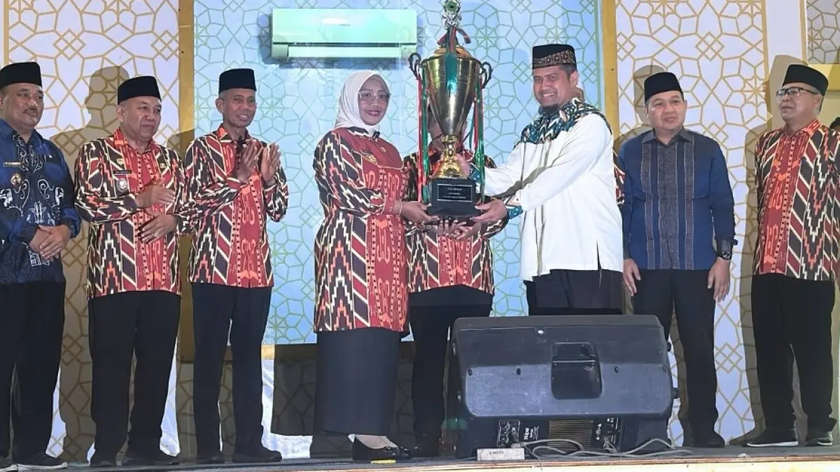 Bupati Mempawah Hj Erlina menyerahkan piala bergilir kepada Plt Camat Mempawah Hilir dalam penutupan MTQ ke-37 tingkat Kabupaten Mempawah, Rabu (29/4) malam. (ISTIMEWA)