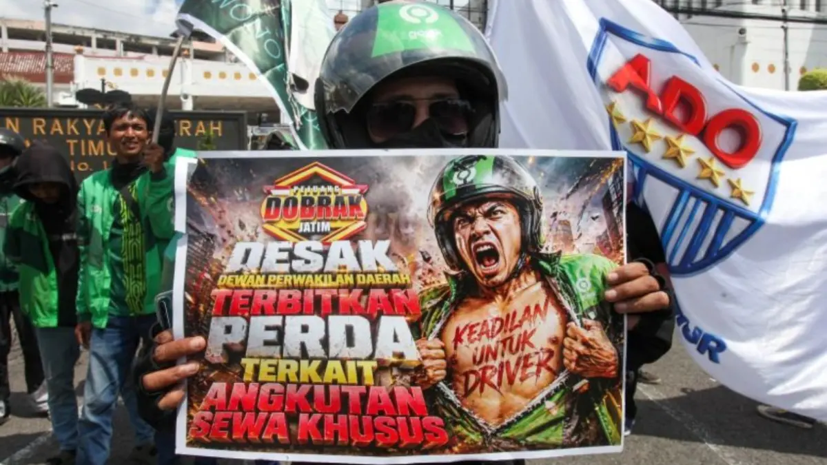 Pengemudi ojek daring membentangkan poster saat berunjuk rasa di Gedung DPRD Provinsi Jawa Timur, Surabaya, Jawa Timur, Selasa (28/4). (ANTARA FOTO/Didik Suhartono/kye)