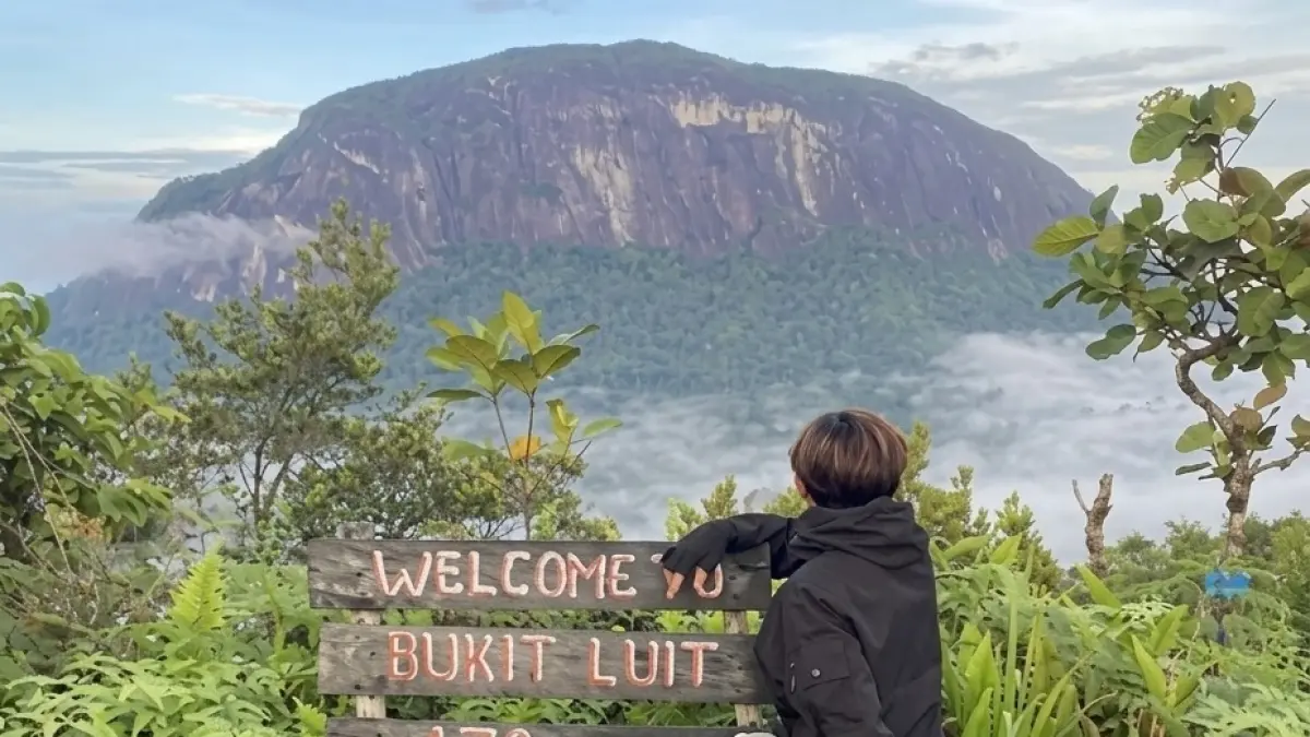 Pendaki menikmati pemandangan di salah satu bukit dengan latar Bukit Kelam. 