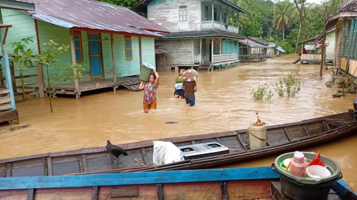 Warga melintasi banjir yang menenggelamkan jalan di salah satu desa di Kecamatan Silat Hulu. (ISTIMEWA)