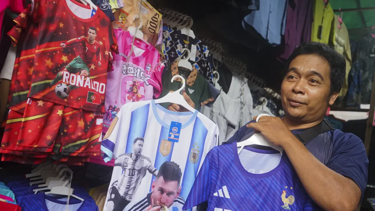 JERSEY: Pedagang pakaian di Pasar Tengah memperlihatkan jersey Piala Dunia dengan motif pemain bintang dunia yang menarik banyak konsumen. (HARYADI/PONTIANAKPOST)
