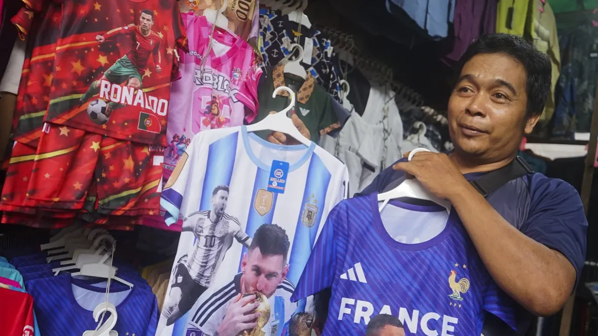 Pedagang pakaian di Pasar Tengah memperlihatkan jersey Piala Dunia dengan motif pemain bintang dunia yang menarik banyak konsumen. (HARYADI/PONTIANAKPOST)